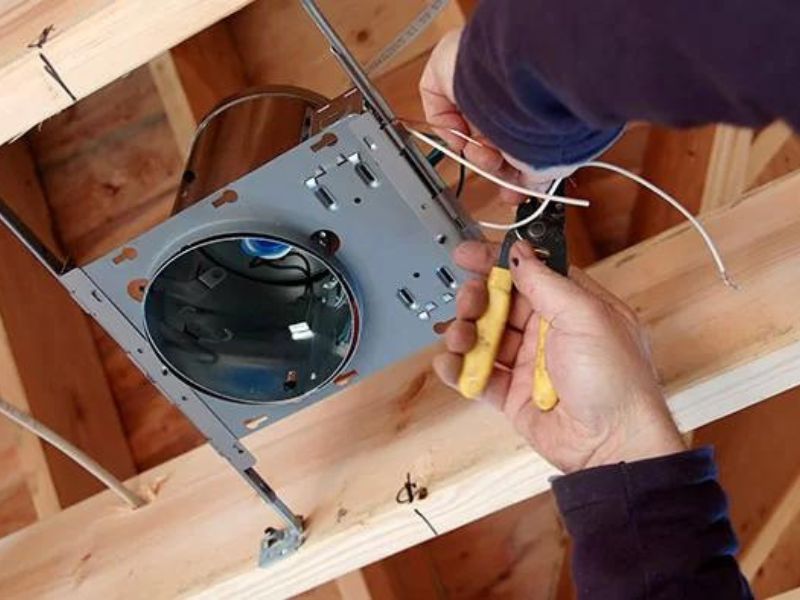 A licensed electrician installing a ceiling fan in a residential home.